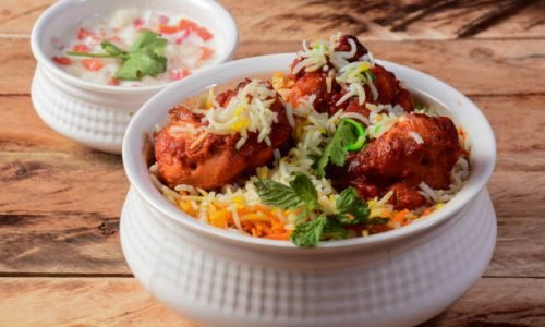 Chicken Tikka Biryani made of Basmati rice cooked with masala spices, served with yogurt, selective focus